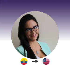 A woman with long dark hair in a light blue suit with glasses smiles at the camera. Ecuador flag points to the US flag.
