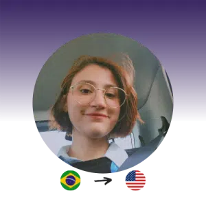 A woman with short brown hair and glasses smiles at the camera. The Brazilian flag points to the U.S. flag.